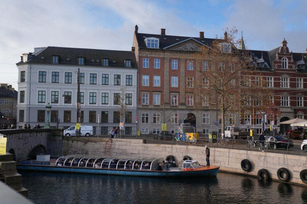 Canal tour boat passing Copenhagen waterfront buildings