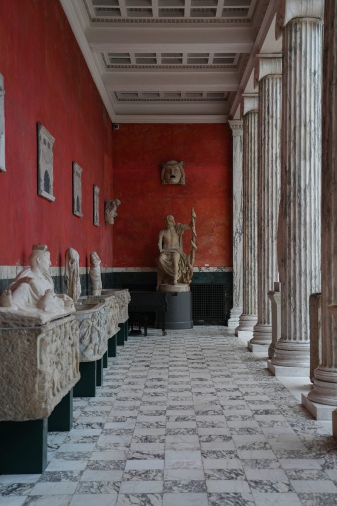 Classical sculpture gallery with red walls at Ny Carlsberg Glyptotek