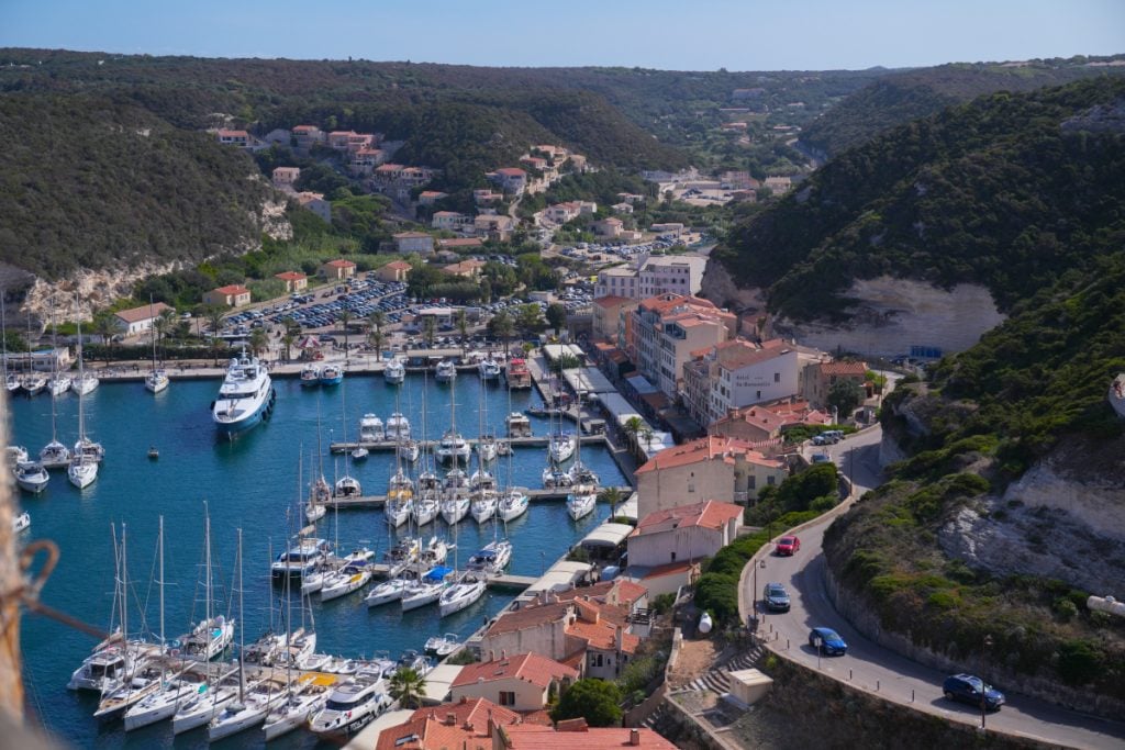 Sailboats docked in Bonifacio's marina between tall limestone cliff walls