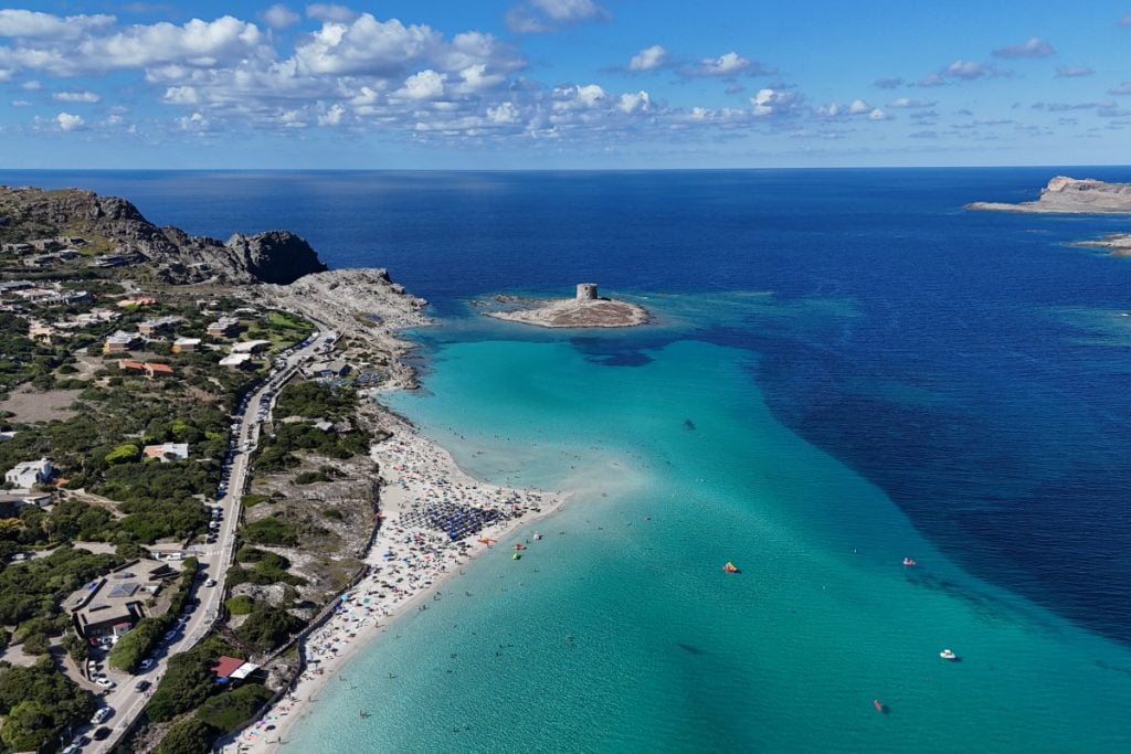 Shallow turquoise water and white sand at La Pelosa beach in Sardinia