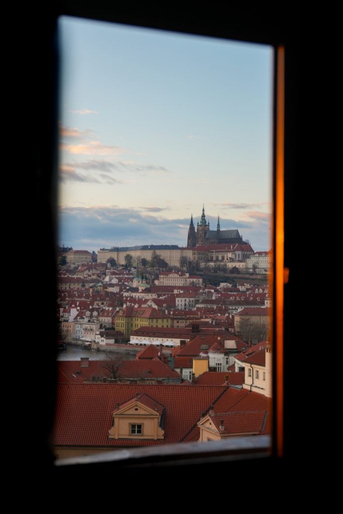 Prague Castle framed by a window at sunset