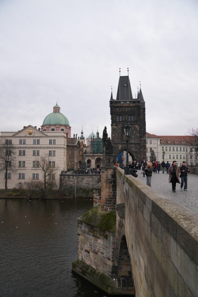 Pedestrians crossing Charles Bridge toward Old Town Bridge Tower