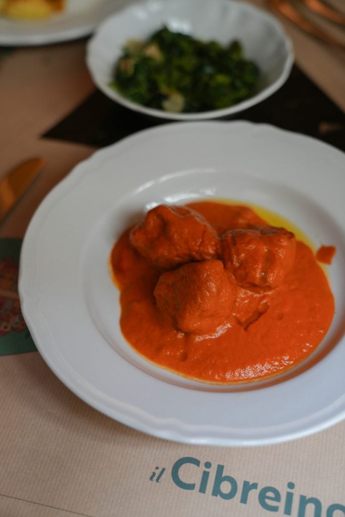 Sauced entrée with a side of greens at Cibrèo Trattoria