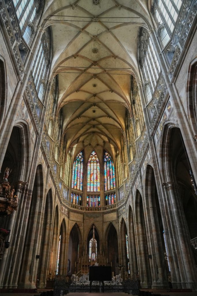 Vaulted nave and stained-glass window inside St. Vitus Cathedral