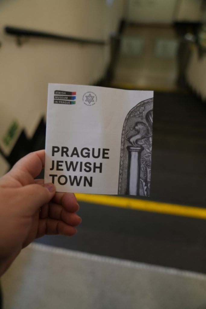 Hand holding a Prague Jewish Town visitor guide