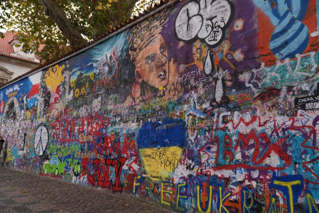 Colorful graffiti and portraits covering the Lennon Wall
