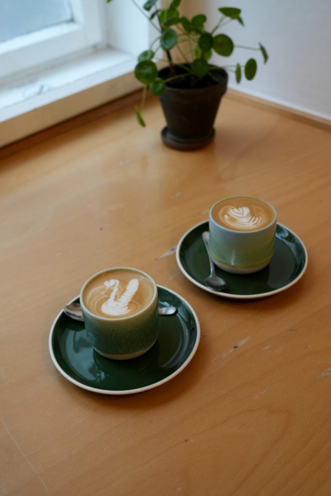Two green cups of coffee on a table at Onesip