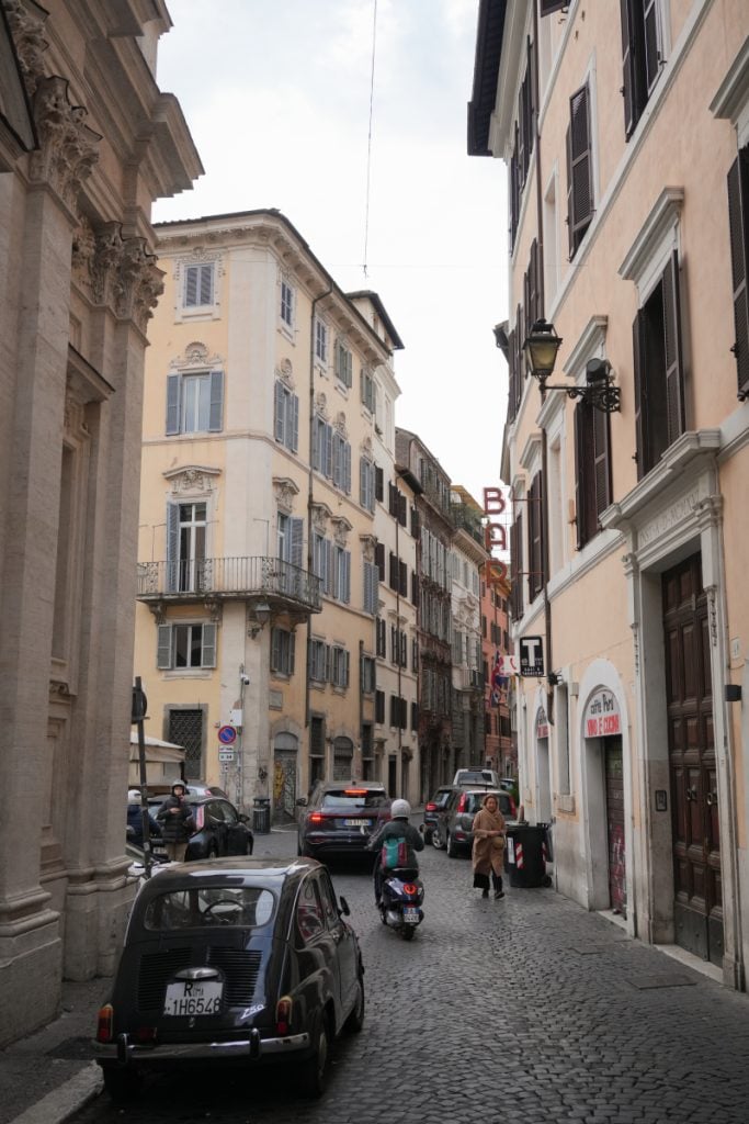 Cars and scooter on a cobblestone street in Regola, Rome