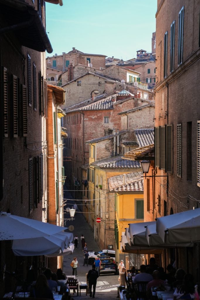 Steep street lined with brick buildings in Siena