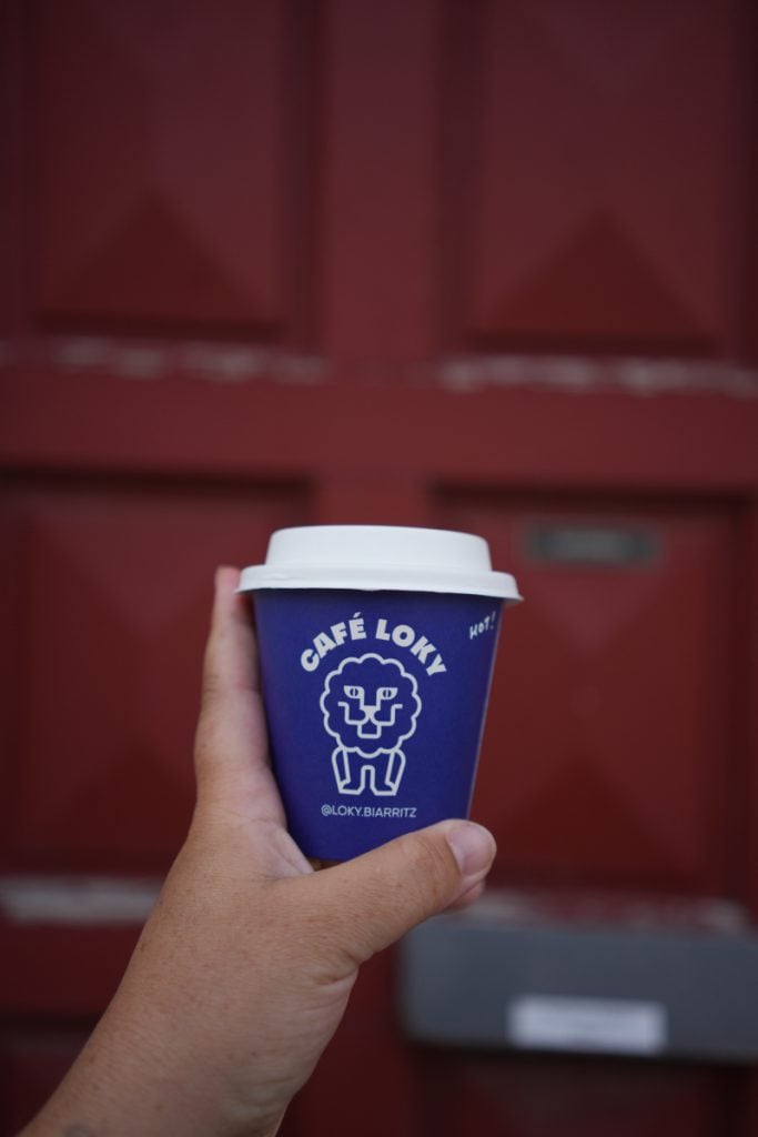 Hand holding a blue Café Loky takeaway cup
