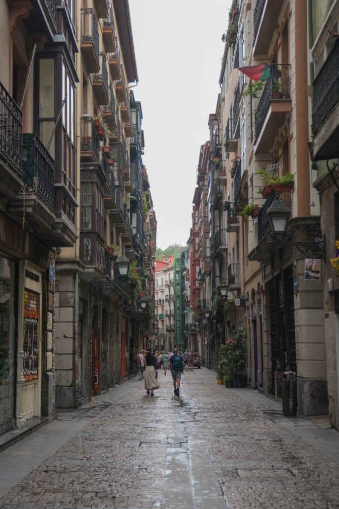 Pedestrians walking a cobblestone street in Bilbao’s Casco Viejo