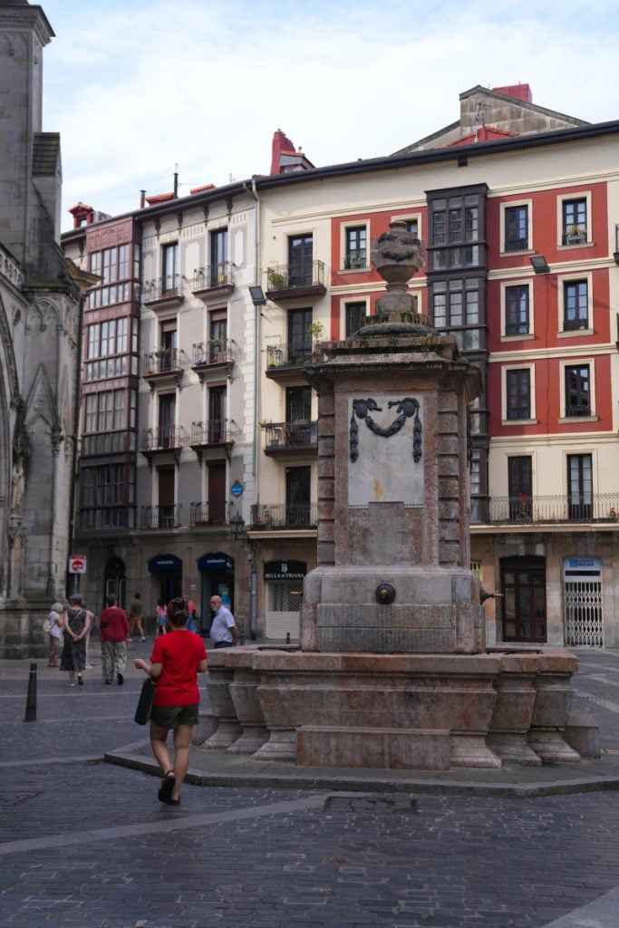 Stone fountain and colorful buildings in Bilbao’s Casco Viejo