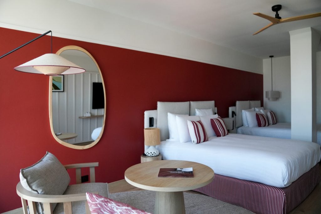 Le Talaia guest room with two beds and red accent wall