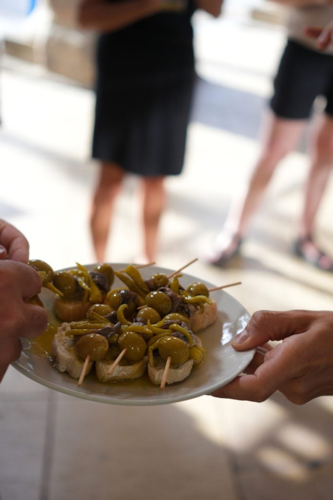 Hands passing a platter of gilda pintxos