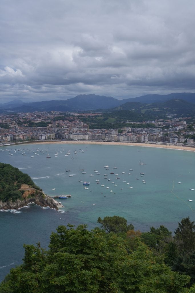 Sailboats anchored in San Sebastián Bay under cloudy skies