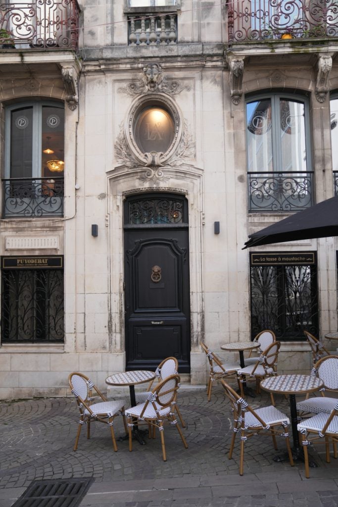Café tables outside an ornate stone building in Bayonne