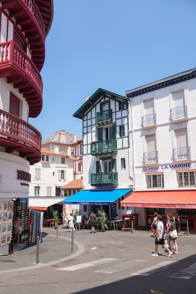 Pedestrians passing cafés and colorful balconies in central Biarritz