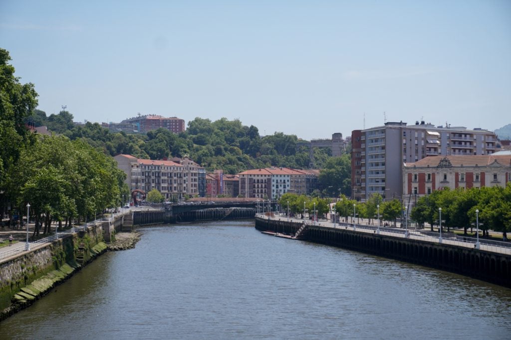 Bilbao riverfront lined with trees and apartment buildings