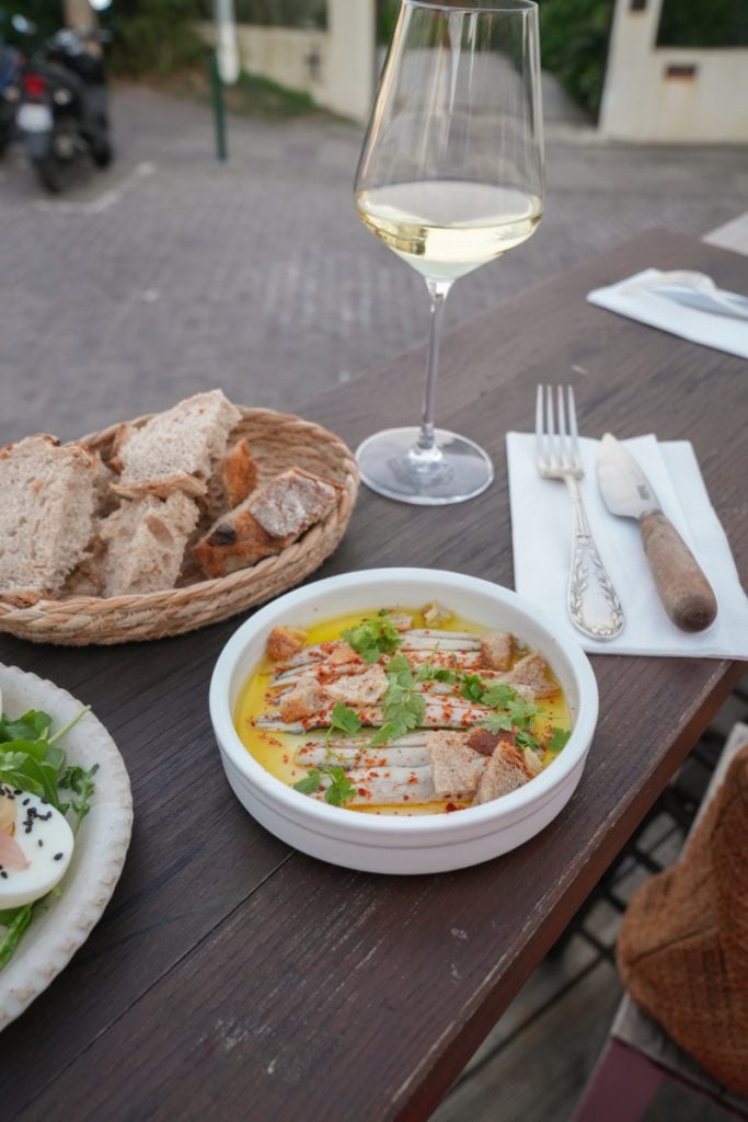 Fish dish with croutons, bread, and wine at Chéri Bibi