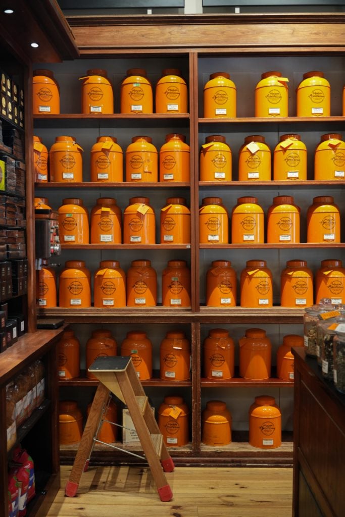 Orange tea canisters lining shelves at Maison Arostéguy