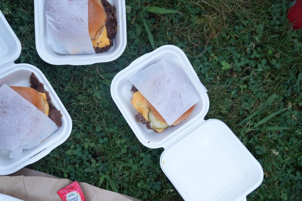 Nelly's cheeseburgers in takeaway boxes on grass