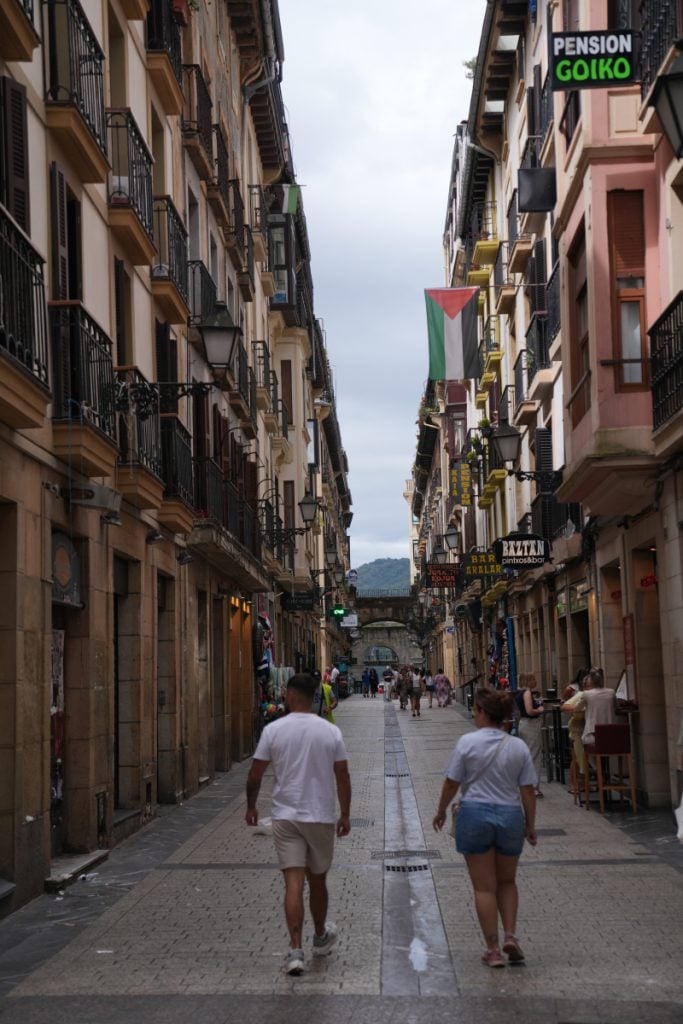 Pedestrians walking through San Sebastián's balcony-lined Old Town