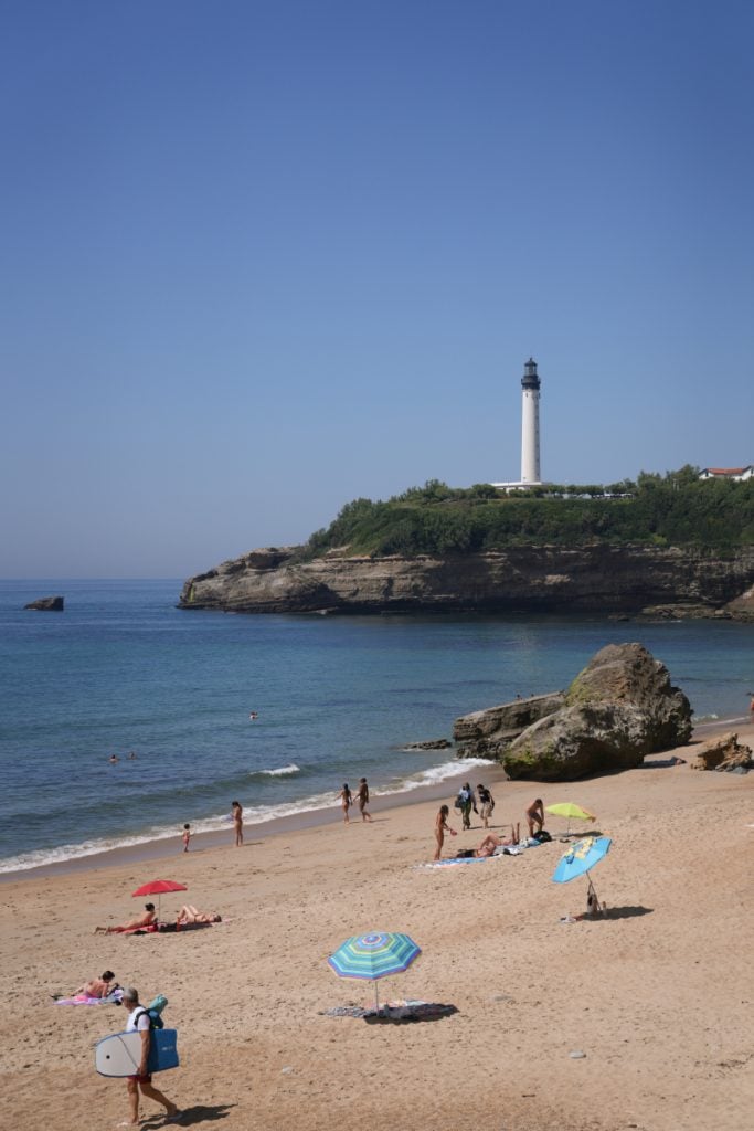 Biarritz lighthouse above beachgoers at Plage Miramar