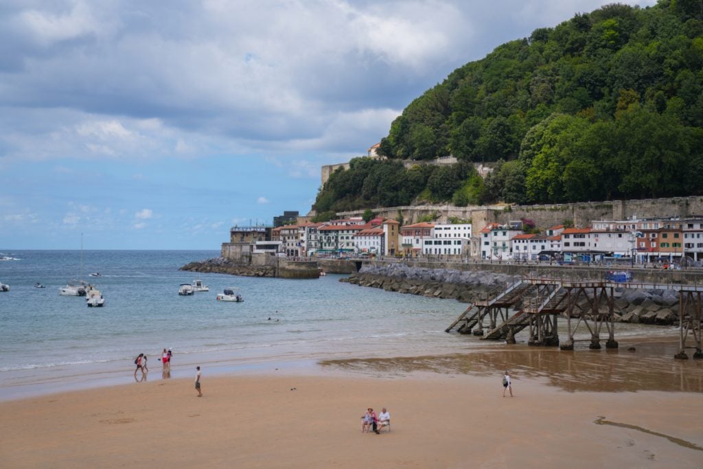 Beachgoers beside boats in La Concha Bay