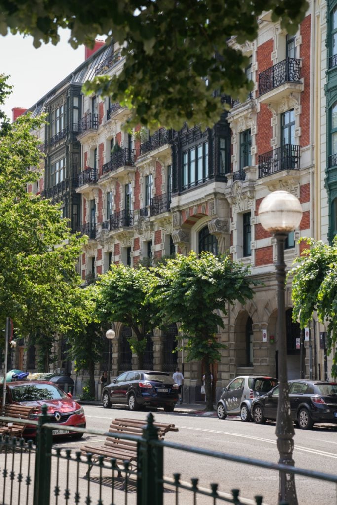 Tree-lined street with ornate buildings in Abando