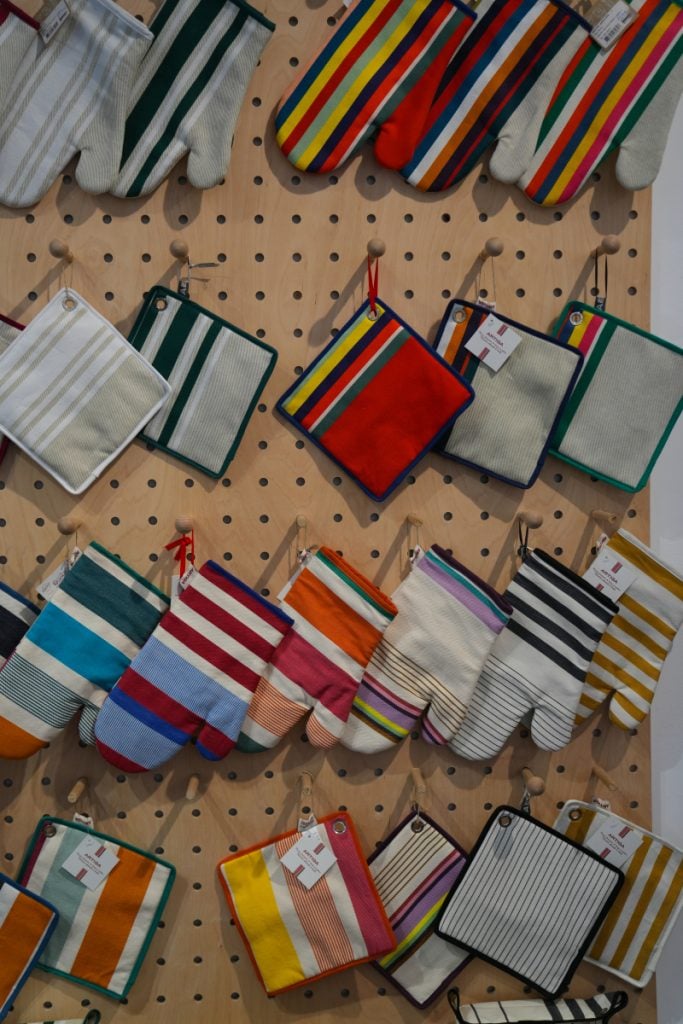 Striped oven mitts and potholders displayed on pegboard at Artiga