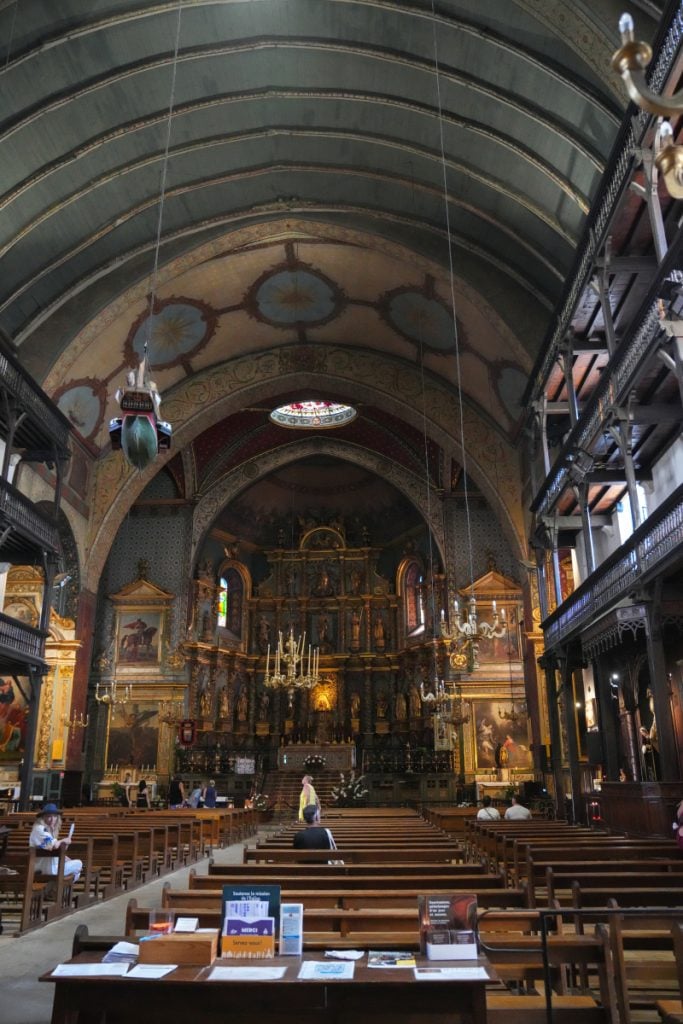 Ornate interior of Église Saint-Jean-Baptiste with wooden galleries