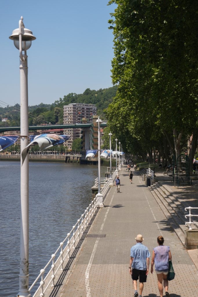 People walking along the Nervión River promenade in Bilbao