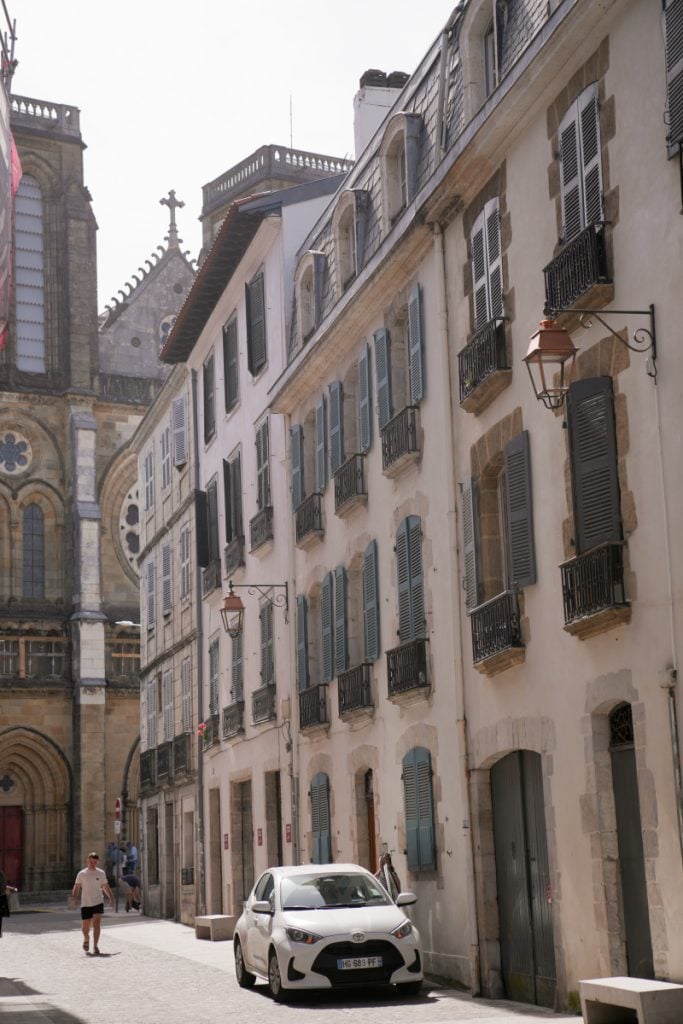 Shuttered buildings and a church along a Petit Bayonne street