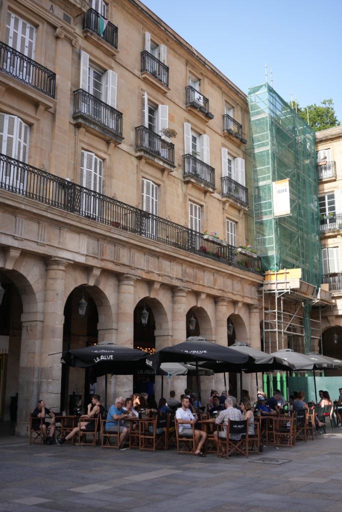 Café tables beneath Plaza Nueva's stone arcades in Bilbao