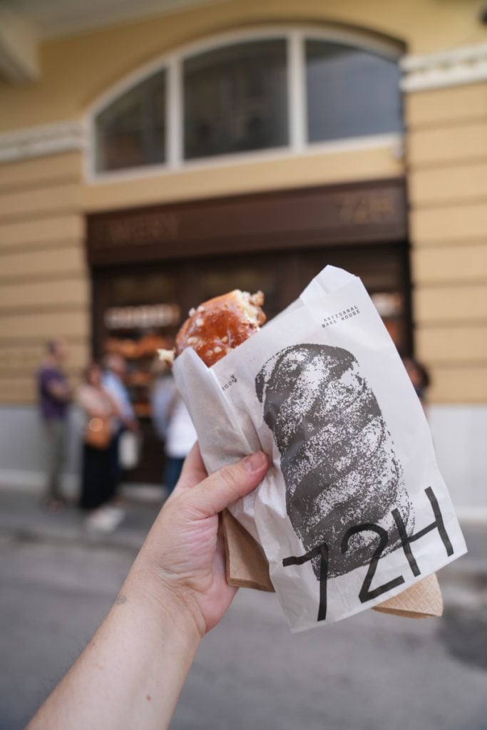 Hand holding a pastry outside 72H bakery