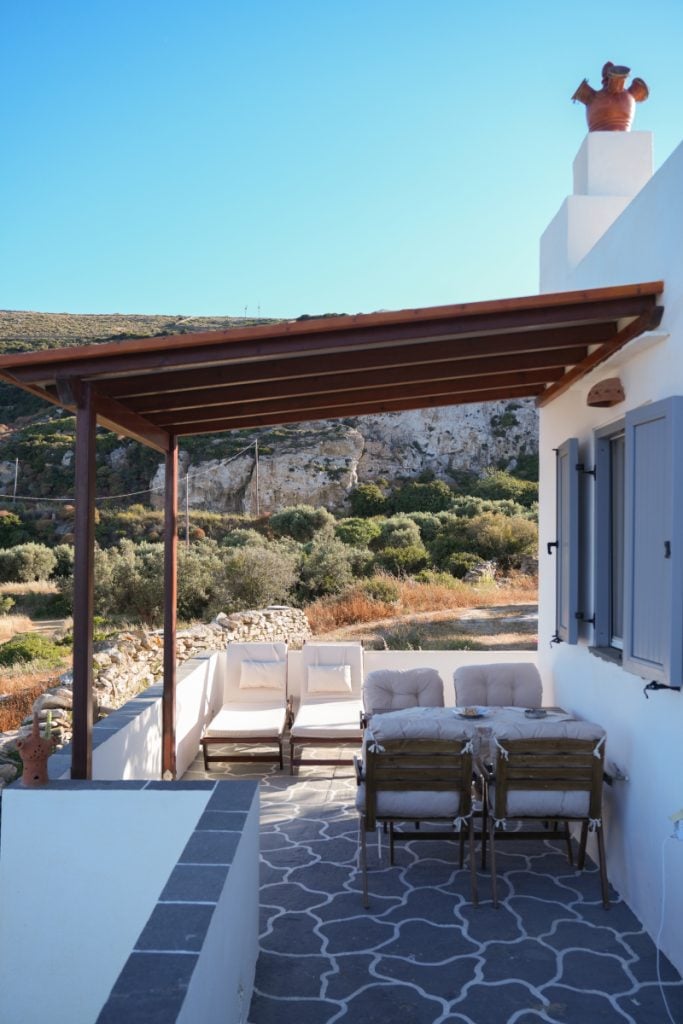 Covered dining patio at Aggelis Villa with stone paving and hillside views.
