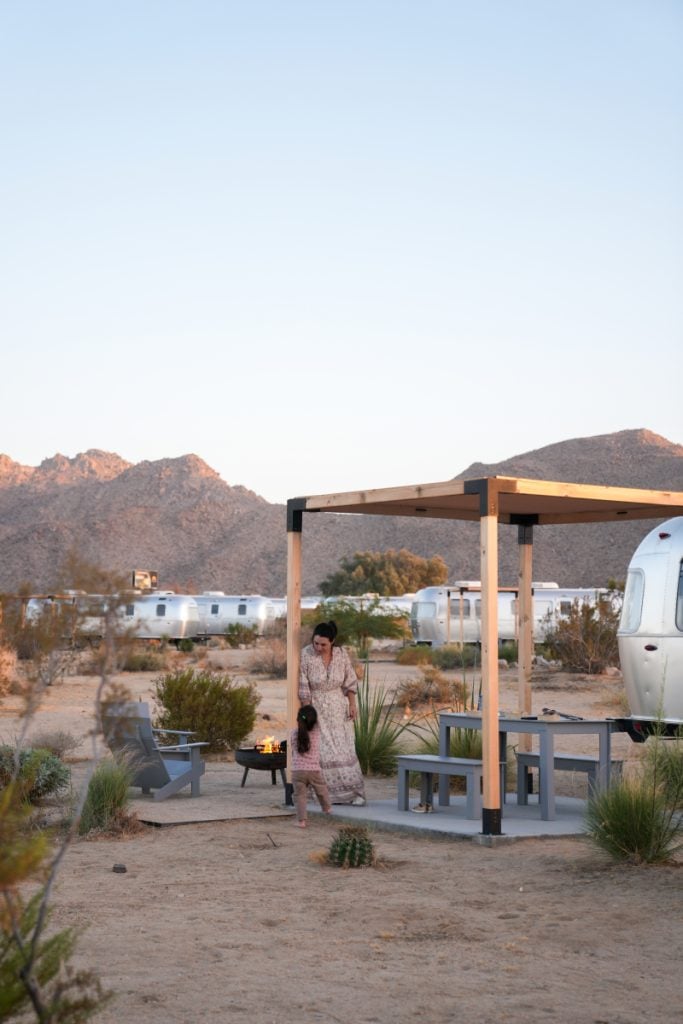 Adult and child beside an Airstream patio and fire pit at AutoCamp Joshua Tree