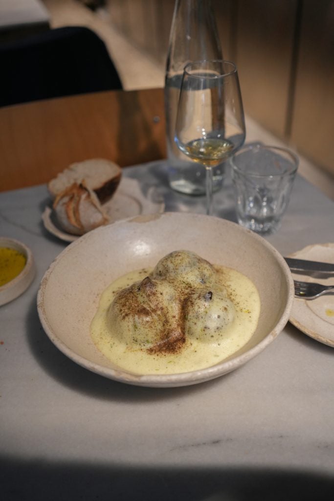 Creamy dish served with bread and wine at Akra