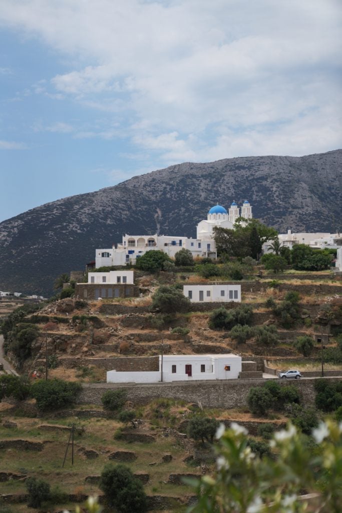 White hillside buildings and a blue-domed church in Apollonia.