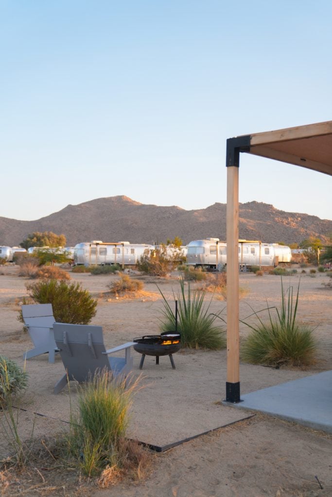 Patio chairs and a fire pit overlooking Airstream trailers at AutoCamp Joshua Tree
