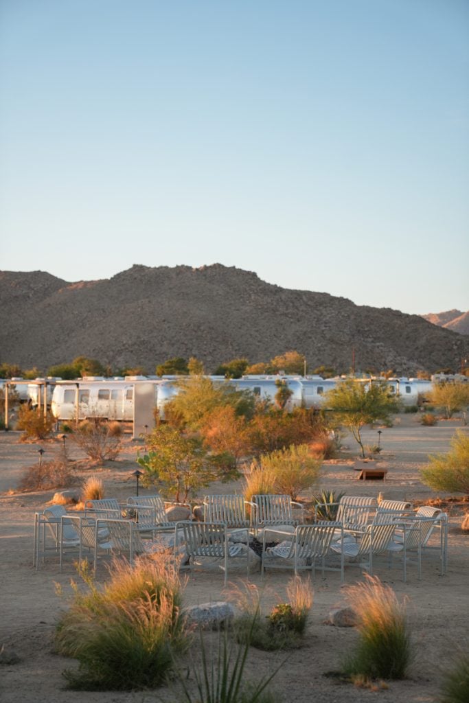 Circle of outdoor chairs with Airstream trailers and mountains at AutoCamp Joshua Tree