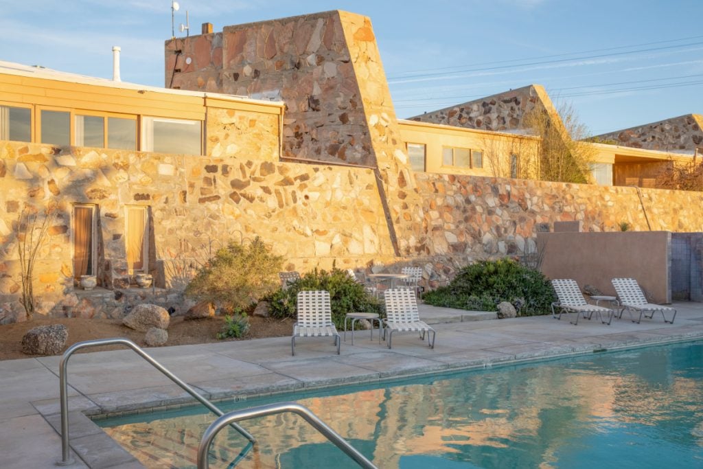 Pool and loungers beside a stone building at The Bungalows at Retreat by Homestead Modern