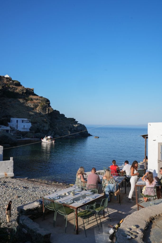 Cantina diners seated beside a rocky seaside cove