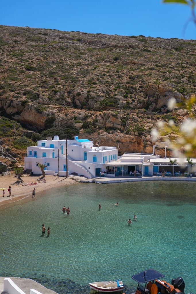 Swimmers in the clear bay beside white waterfront buildings in Cheronissos.