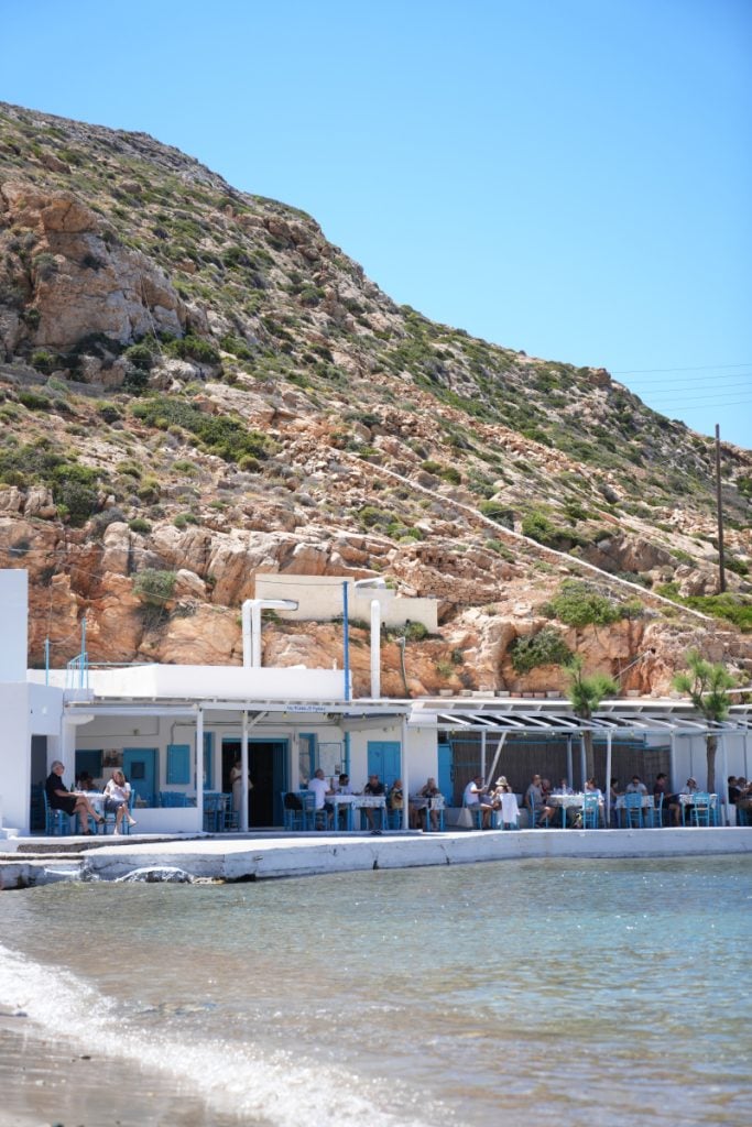 Beachfront taverna below a rocky hillside in Cheronissos