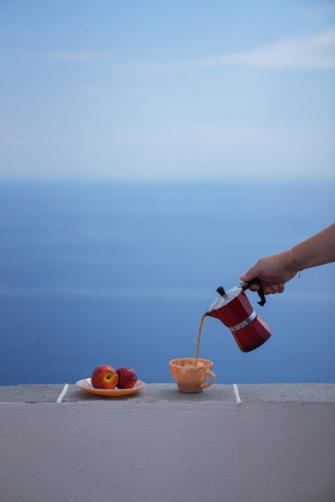 Coffee poured from a moka pot beside the sea