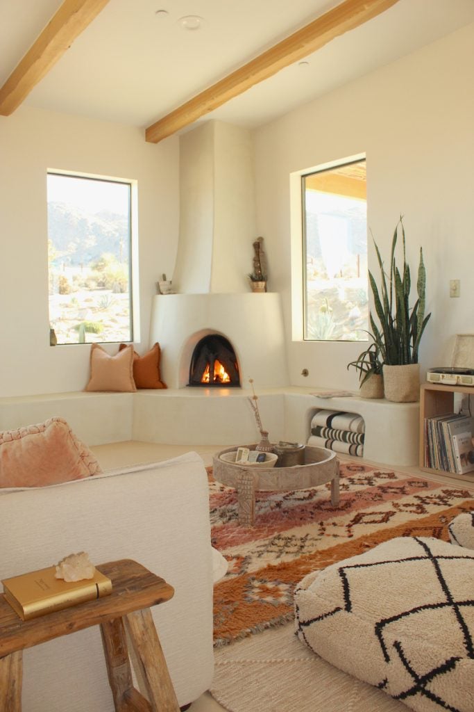 Desert Wild Home living room with a corner fireplace, wood beams and patterned rugs