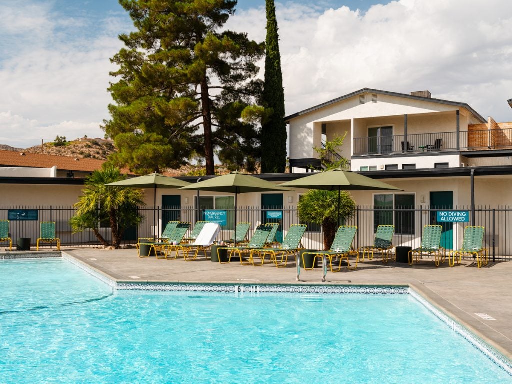Pool with green loungers and umbrellas at Field Station Joshua Tree