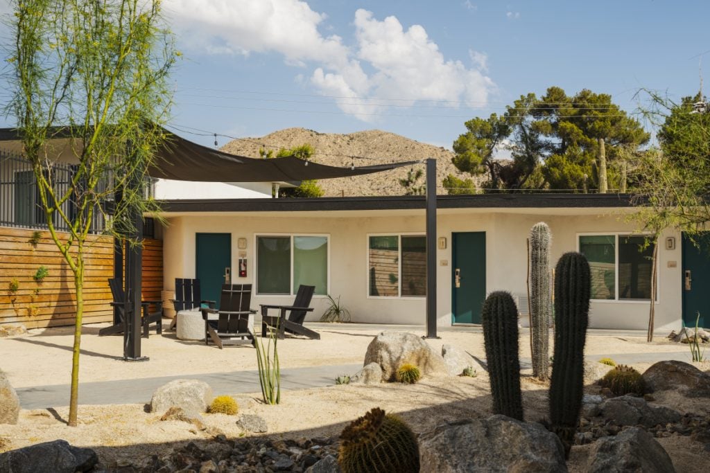 Field Station Joshua Tree rooms with green doors, shaded seating and desert landscaping
