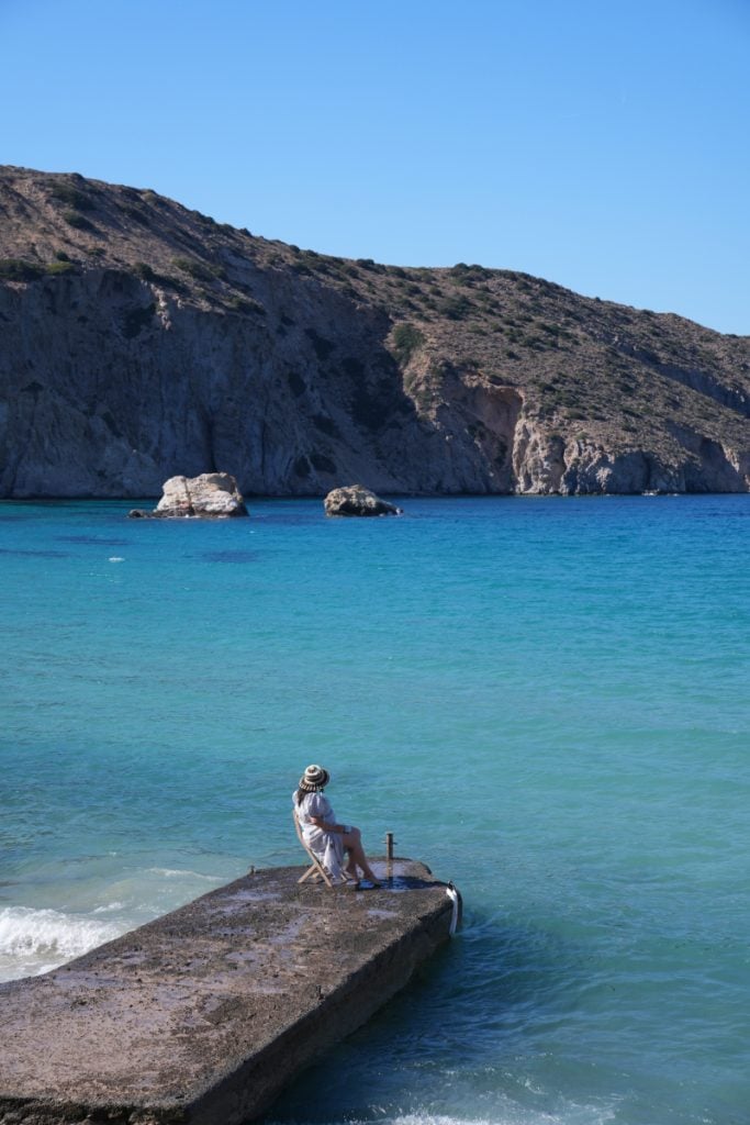 Woman seated on a pier overlooking Firopotamos Bay